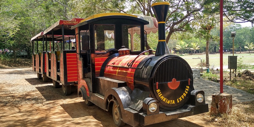The image shows a colourful, kids toy train in Kishkinta, moving through a scenic area