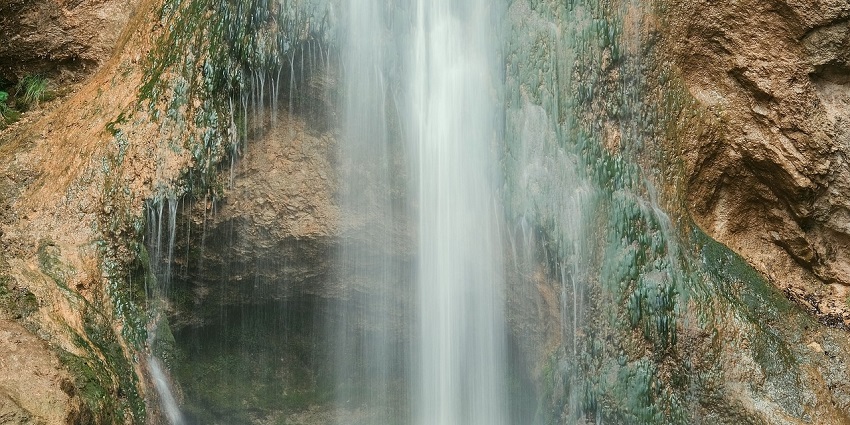 A waterfall flowing into a tranquil pool, framed by lush vegetation for all to explore.