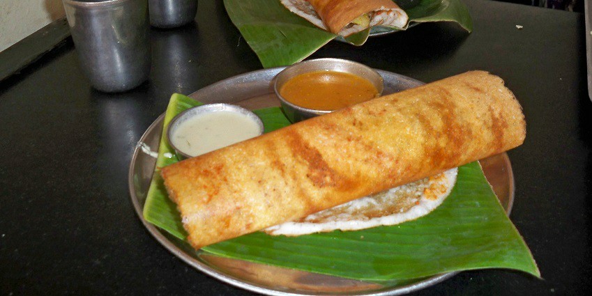 Plate of masala dosa served with chutney and spicy curry
