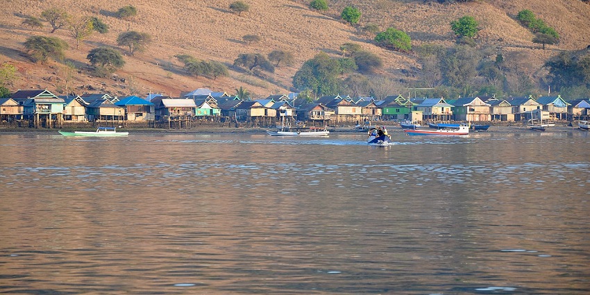 Distant view of a Komodo village from the serene waters of the island
