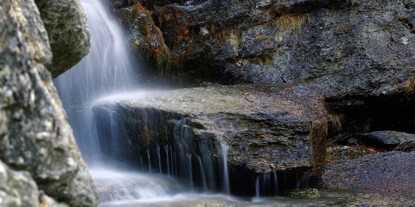 Image of close view of a waterfalls cascading through huge rocks and clear water