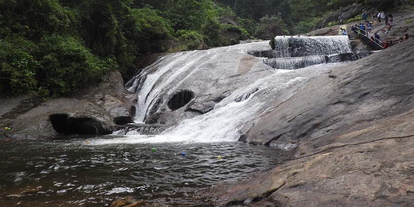 A picture of a waterfall with water cascading down a rocky terrain near the Velliangiri Hills