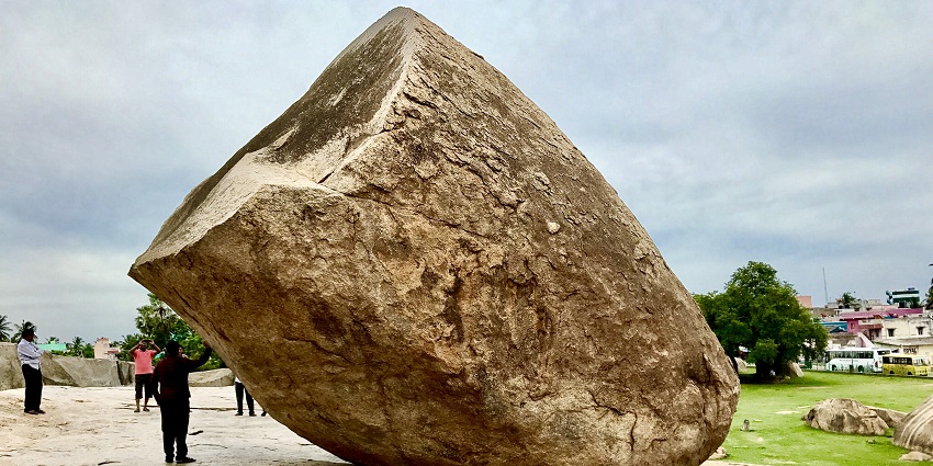 Massive granite boulder precariously balanced on a hillside.