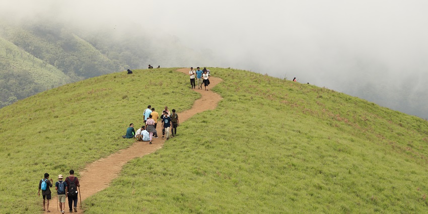 A serene shot of hills in Kudremukh during daytime on a cloudy day and people on trek