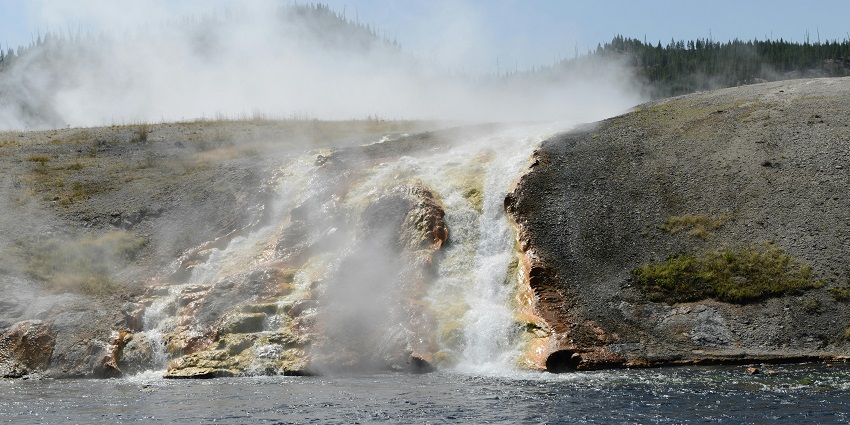 View of silver steaming water streaming into the hot spring