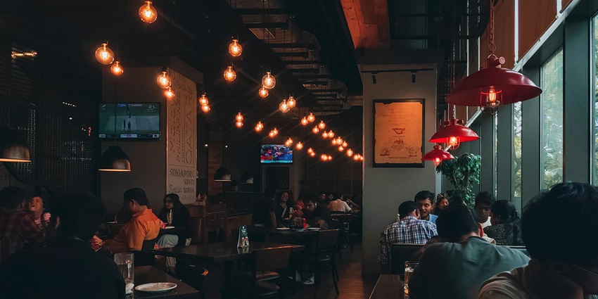 Group of people dining at tables inside a bright, modern restaurant with natural light.