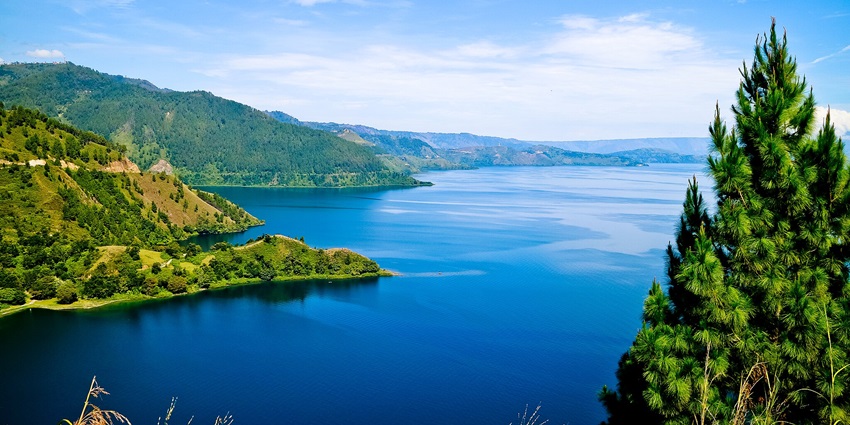 Scenic view of the green mountains surrounding the deep blue waters of the Lake Toba