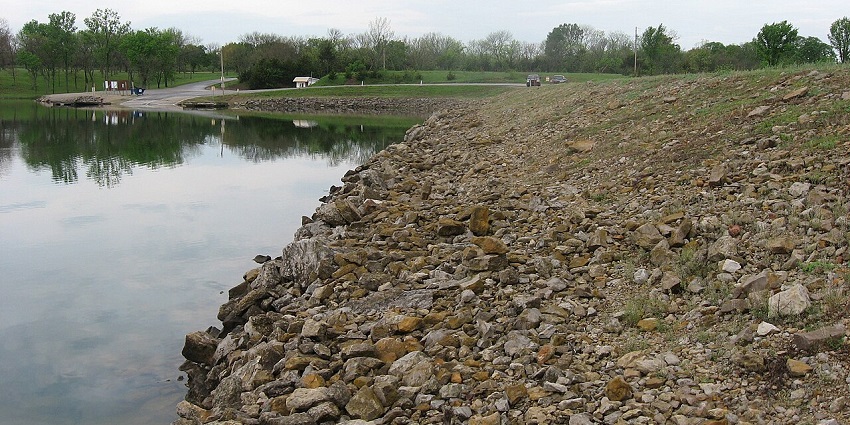 A sloping grassy area near Lake Fort Scott, with trees and clear blue skies in the background.