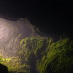 A breathtaking view of a cave in North Goa with lush greenery during the daytime.