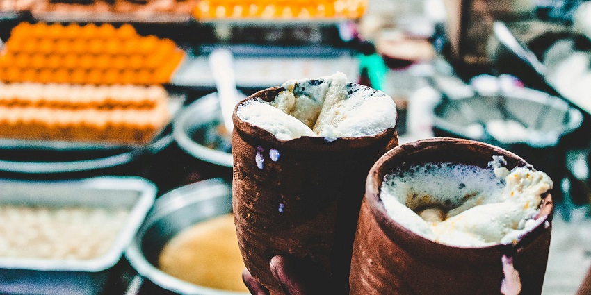 A mouth-watering view of two glasses filled with lassi in a hand during the daytime.