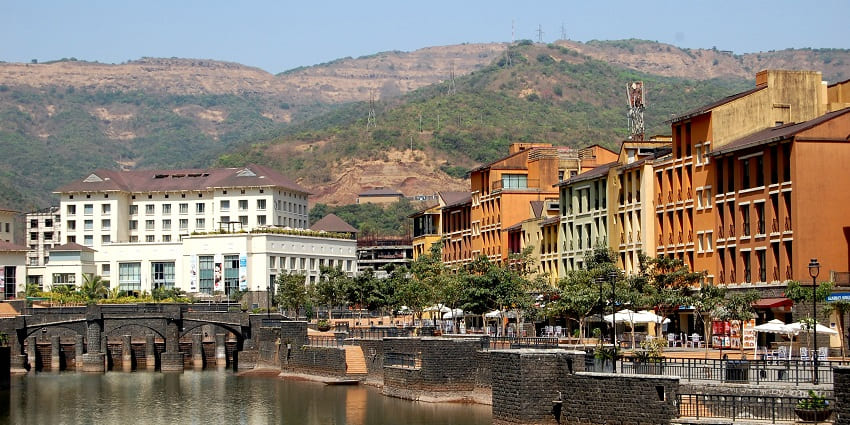 A waterfront view of colourful buildings with a backdrop of hills and a clear sky.