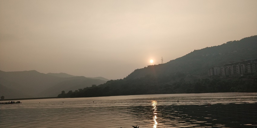 Scenic view of lake in Lavasa during sunset with birds flying over