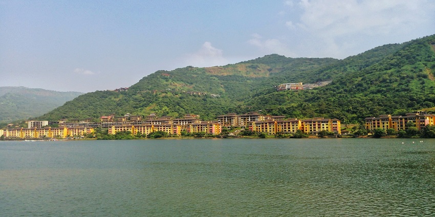 Lavasa city with colorful buildings nestled amidst lush green hills during the daytime.