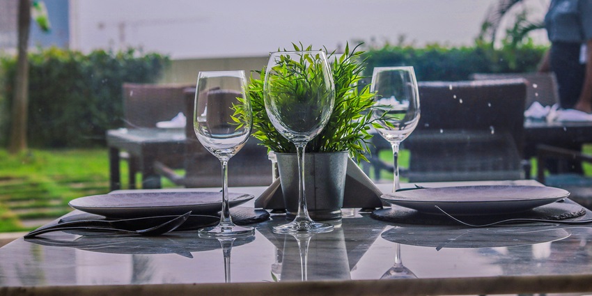Image of a restaurant with dining table decorated with clear wine glasses, plates on the table