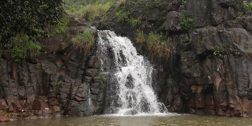 An image view of Lingmala Waterfall, surrounded by vibrant greenery and rocks.