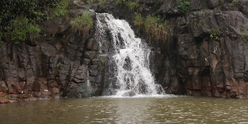 Beautiful Lingmala Waterfall cascading down rocky cliffs surrounded by greenery.