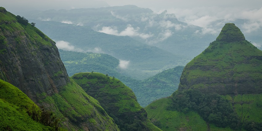 A panoramic view of Lions Point, showcasing greenery, cliffs, and a vibrant sunset sky