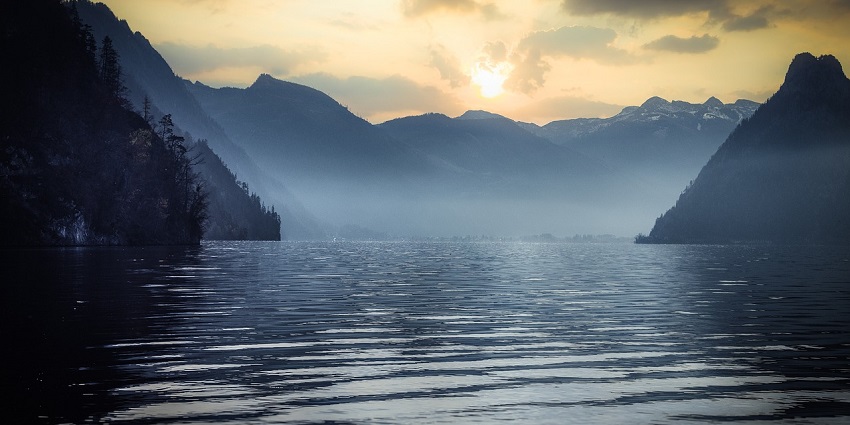 A lake surrounded by majestic mountains under a clear blue sky, reflecting nature's beauty.