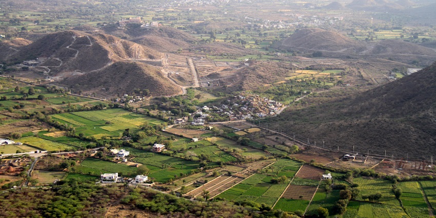 A breathtaking aerial view of a lush green valley with houses and hills during the day.
