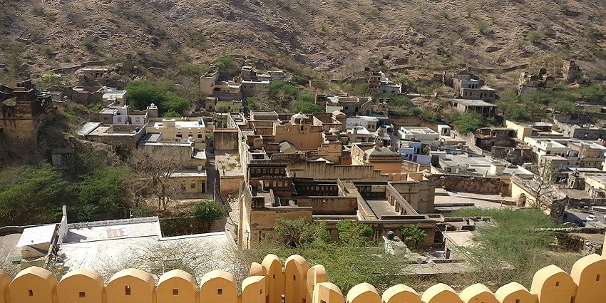 Ancient Amber town in Jaipur with weathered structures blending and rugged landscape.