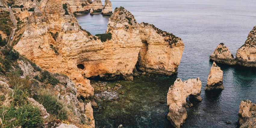 An ancient rock formation with jagged edges, surrounded by calm blue waters near Maharashtra.