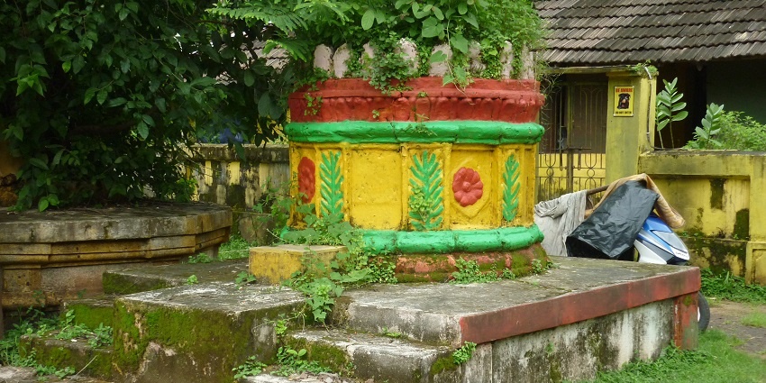The tulsi vrundavan outside the Saptakoteshwar Temple, surrounded by lush greenery.