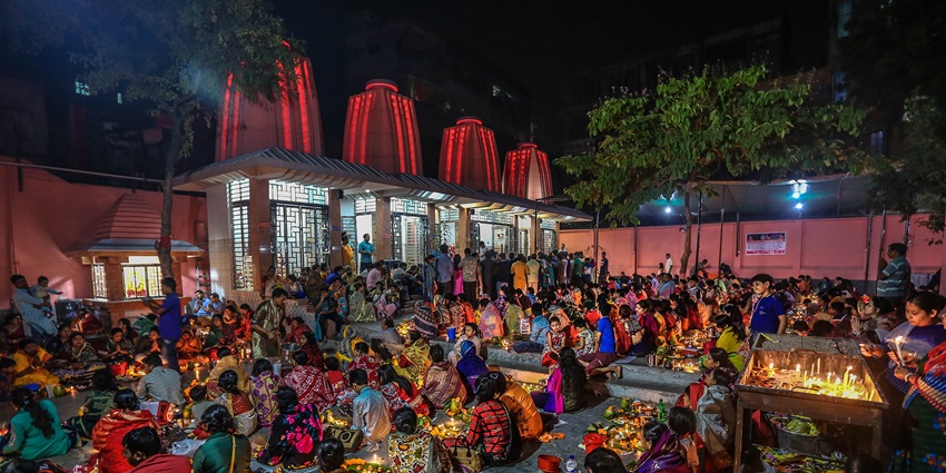 A picture of a puja ceremony happening at a temple during night time with diyas illuminated all around