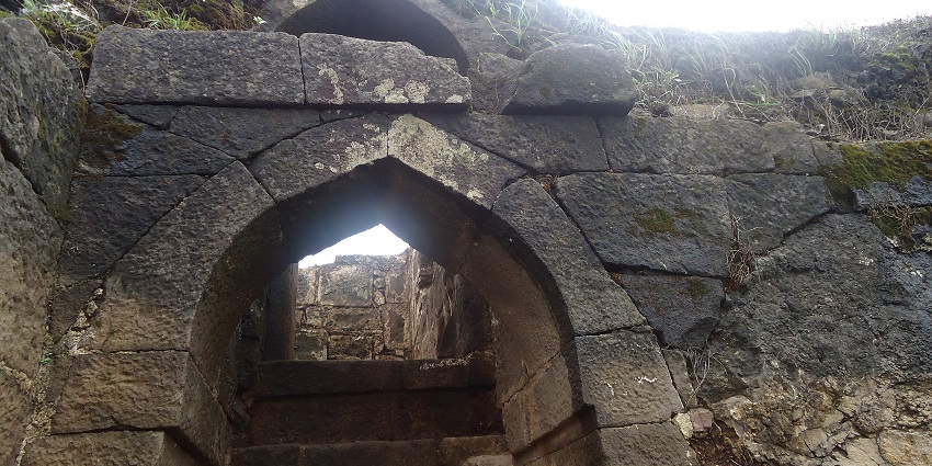 View of Ramshej Fort in Nashik, showing rocky terrain and fort structures on top.