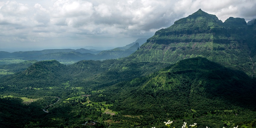 A serene river winds towards a radiant fort, basking in sunlight under a clear blue sky.