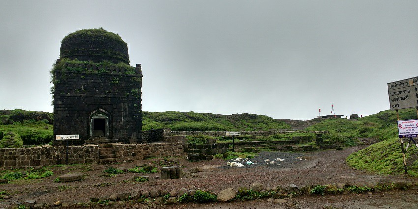 View of Saswad Fort surrounded by lush greenery against the cloudy sky
