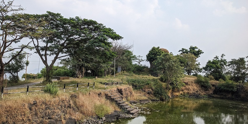 A view of Sajjangad Fort surrounded by greenery and rolling hills in Satara.