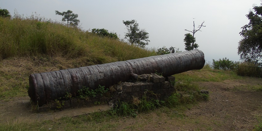 Historic Nau Gaj cannon at Narnala Fort, resting on a stone base amid surroundings