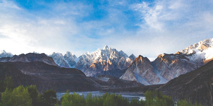 A breathtaking view of the Karakoram mountain range surrounded by lush vegetation.