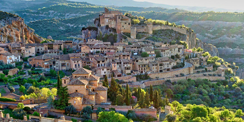 Historical hilltop village with traditional architecture surrounded by lush greenery.