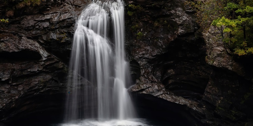 A beautiful waterfall falling into a calm river surrounded by green nature