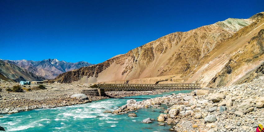 A breathtaking view of a water body flowing through a lush green valley during the day.