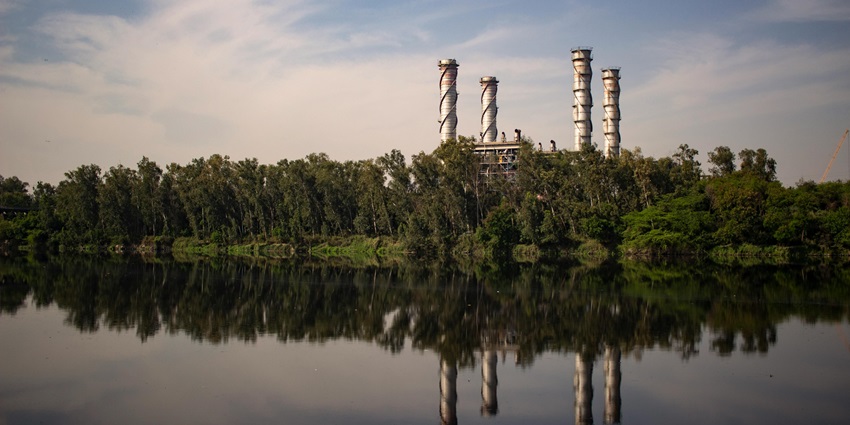 Industrial plant reflected on calm water, showcasing a serene landscape of Delhi.