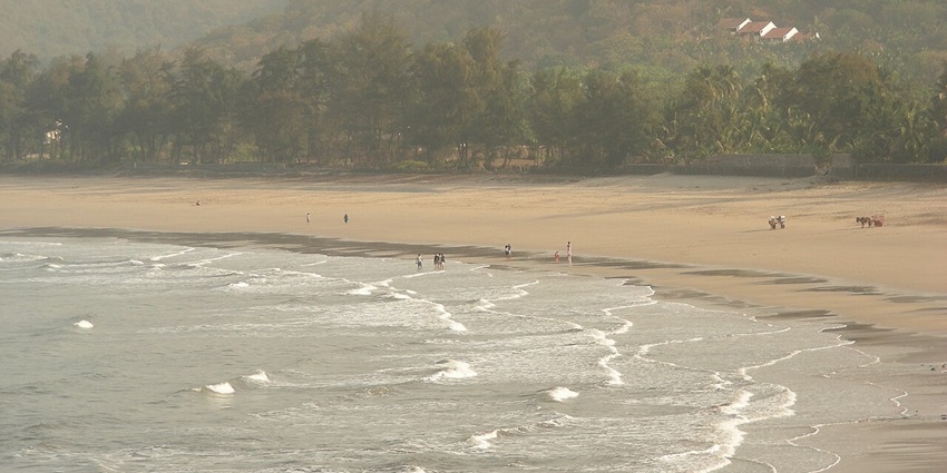 A serene view of Kashid Beach, featuring soft waves and fine white sand under a clear sky