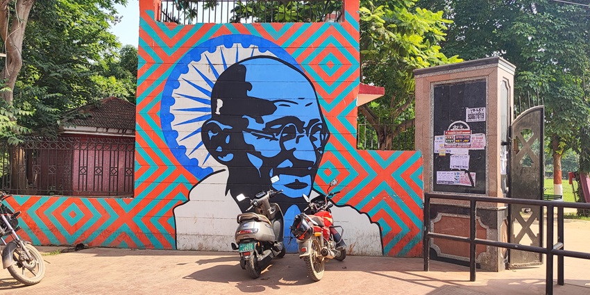 Parking area of Gandhi Maidan with painted walls and vehicles parked near the entry gate