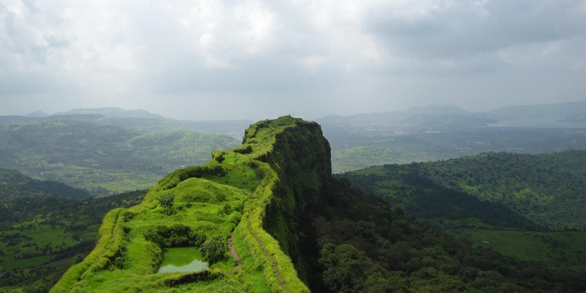 An image of Lohagad Fort with lush greenery surrounding the ancient structures.