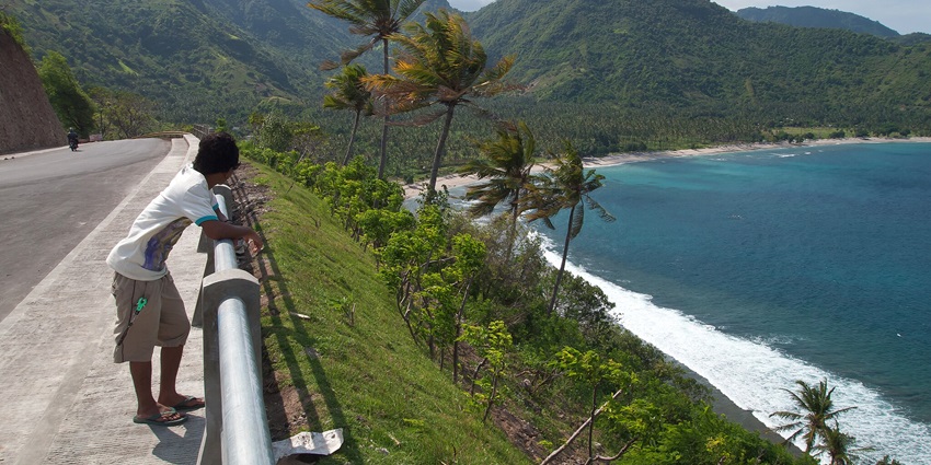 A person enjoying the windy view of Lombok, Island beach in the bay with Palm trees