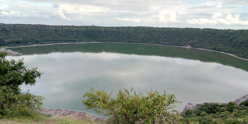 The splendid Lonar Crater Lake is seen from a distance amidst the beautiful setting of an idyllic landscape.