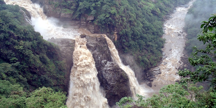 Lush greenery surrounds Magod Falls, showcasing its powerful cascade and rocky terrain.