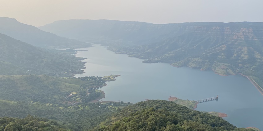A panoramic view of green hills and valleys under a clear blue sky.