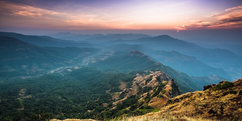 Sunset view over the hills and valleys of Mahabaleshwar with an orange sky.