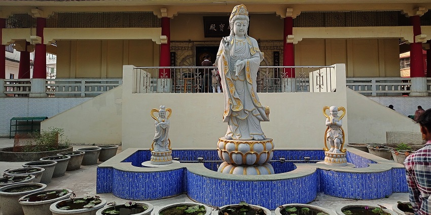 The temple complex at the Mahabodhi temple Monastery has a statue of Budhha and plants.