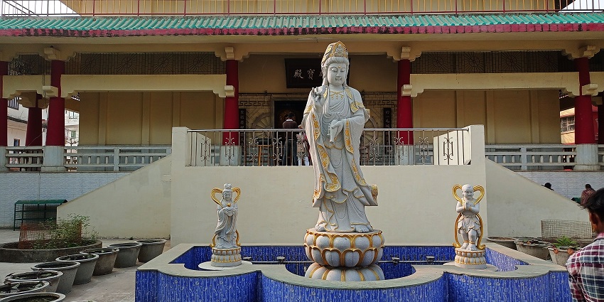 A temple complex at Bodhgaya featuring a pale blue Buddha statue above a lotus.
