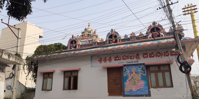 Ornate temple facade with intricate carvings, bustling with devotees under a clear sky