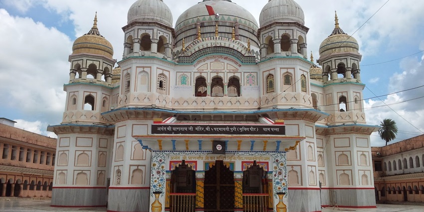 A frontal view of a temple made with white marble, with a massive compound in front