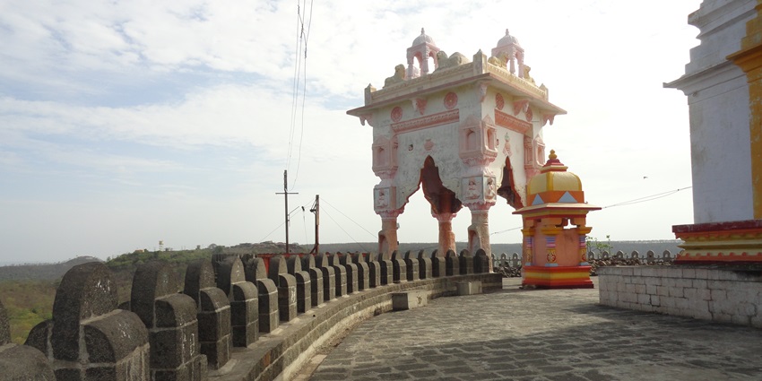 A picture of a temple at the Mahurgad Fort in Maharashtra with views of the scenic township in the background